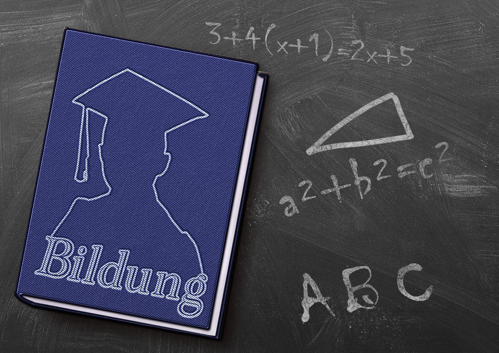 Tafel mit mathematischen Formeln und Buch im Vordergrund