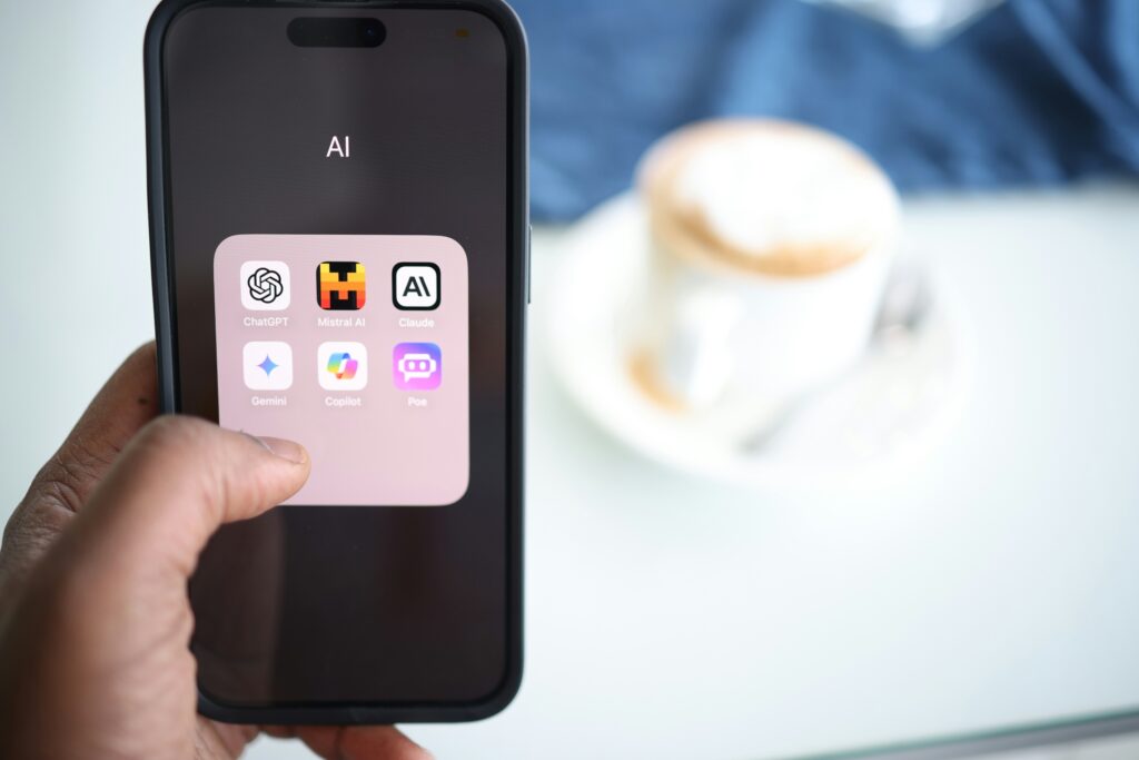 Smartphone mit Apps zur Nutzung von künstlicher Intelligenz. Im Hintergrund eine Kaffeetasse