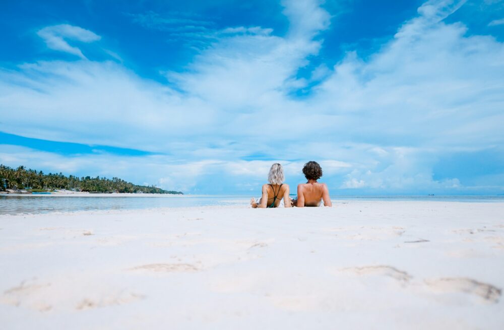 Frau und Mann liegen an einem sonnigen Tag am Sandstrand