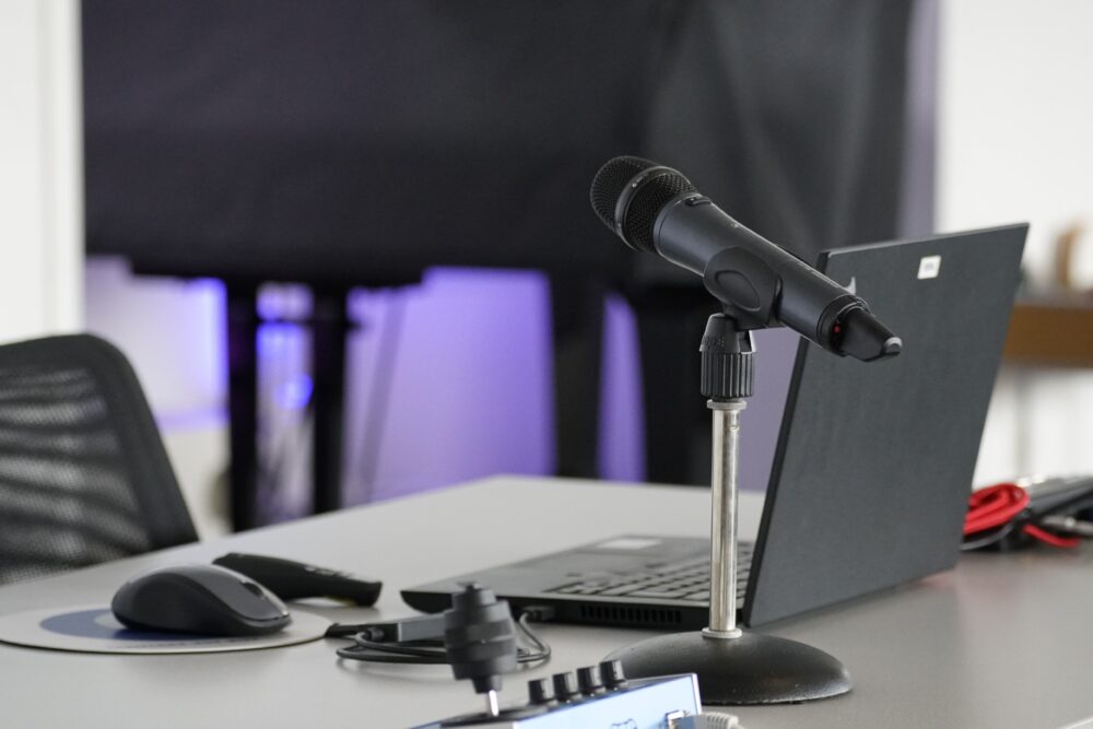Ein Arbeitsplatz mit Laptop, Mikrofon und weiterem digitalen Zubehör