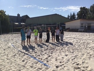 Beach Foto von Schülern, auf dem Beachtennisplatz, die ihre Schläger vors Gesicht halten