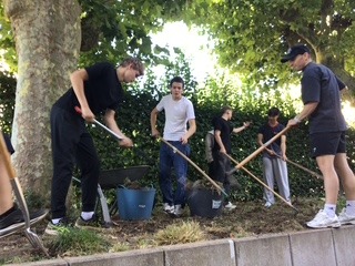 Foto von Schülern, die mit Gartenwerkzeug arbeiten